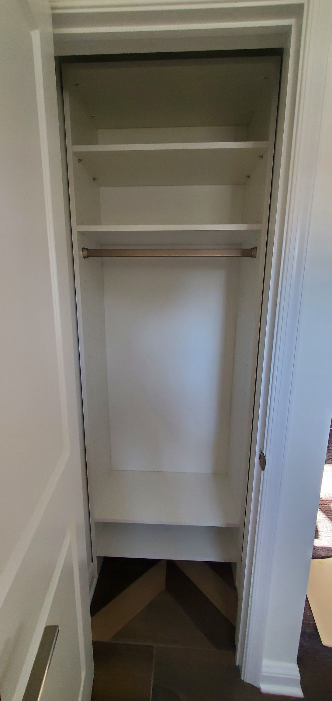 An empty closet with shelves and a hanging rail.