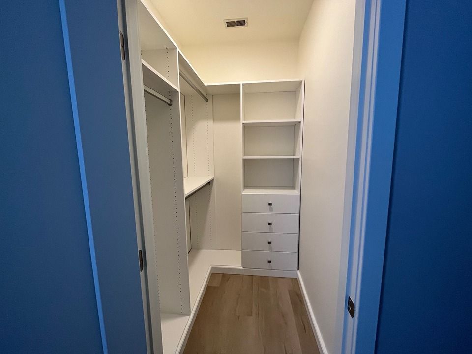 A walk in closet with lots of shelves and drawers in a house.
