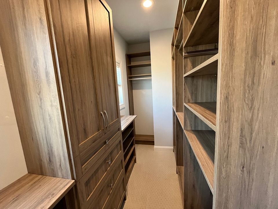 A walk in closet with wooden cabinets and shelves.