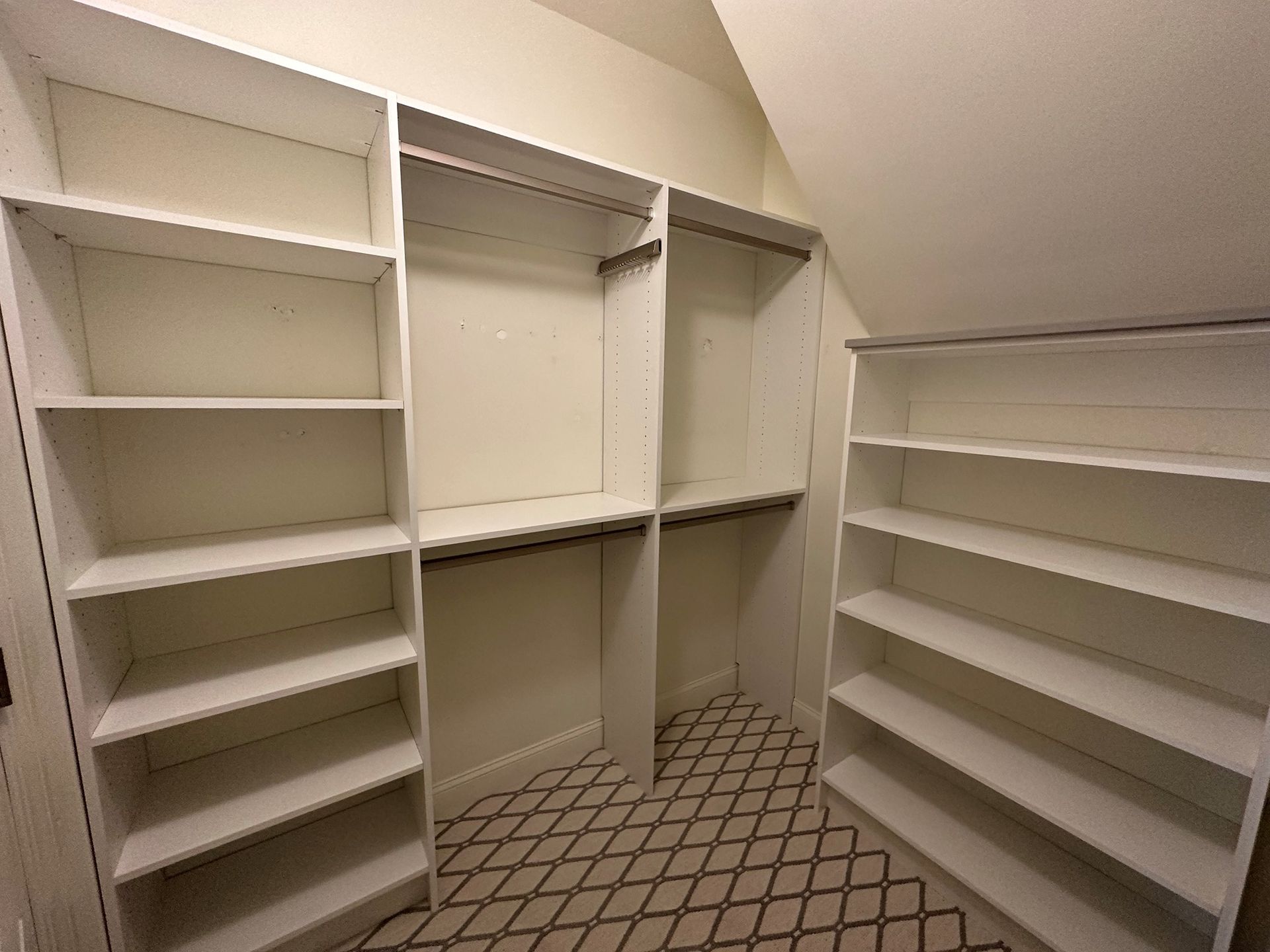 A walk in closet with white shelves and a patterned floor.