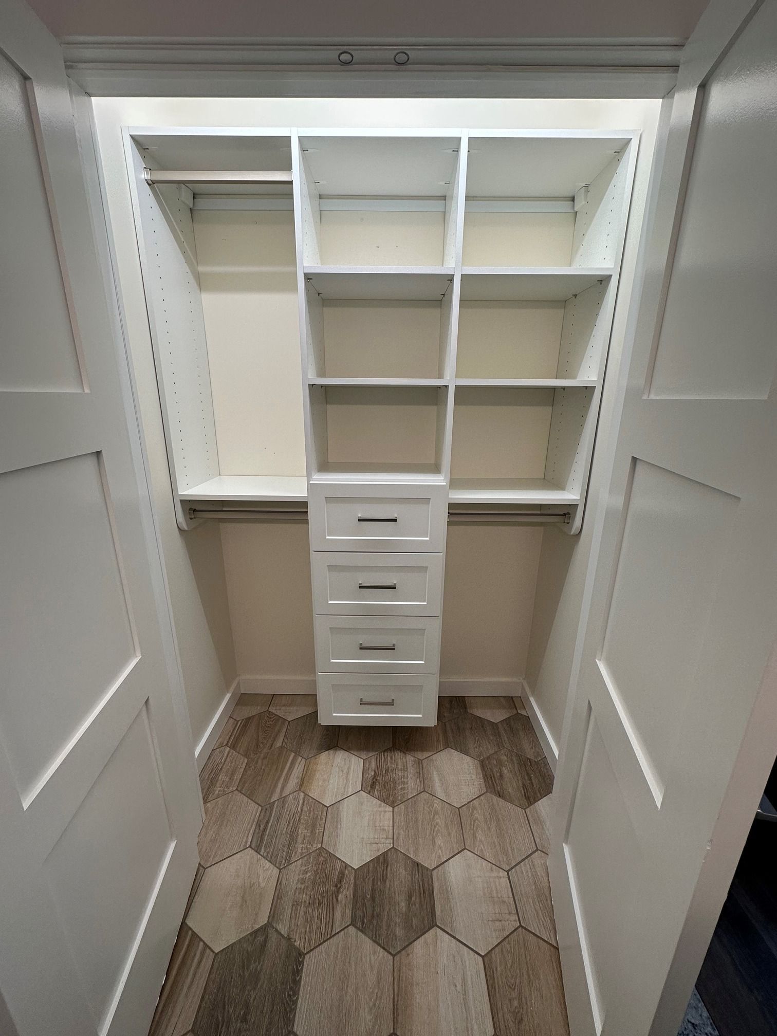 A walk in closet with lots of shelves and drawers.