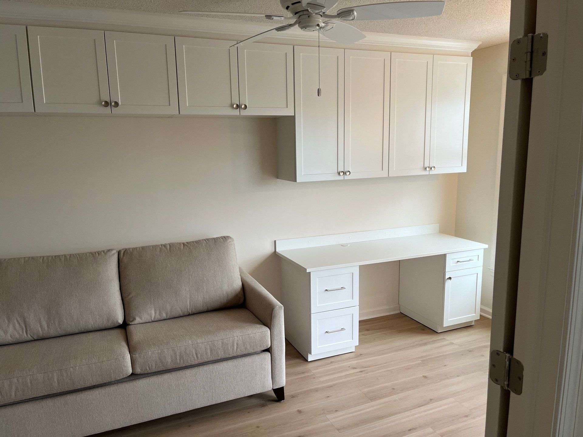 A living room with a couch , desk and cabinets