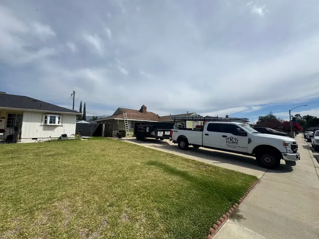 Suburban street with a white work truck parked by a grassy lawn under a cloudy sky
