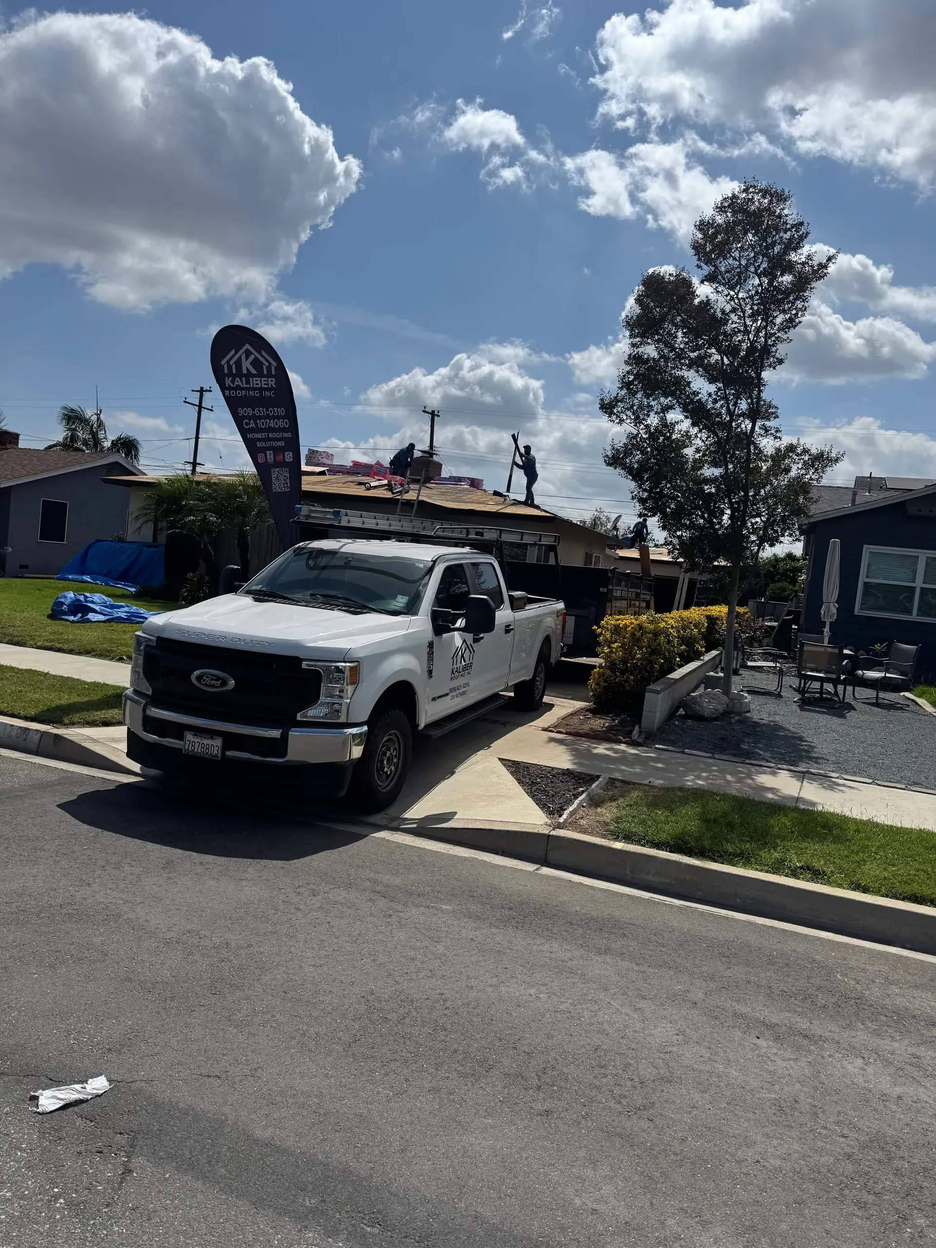 White pickup truck parked outside a building under a cloudy sky with people nearby
