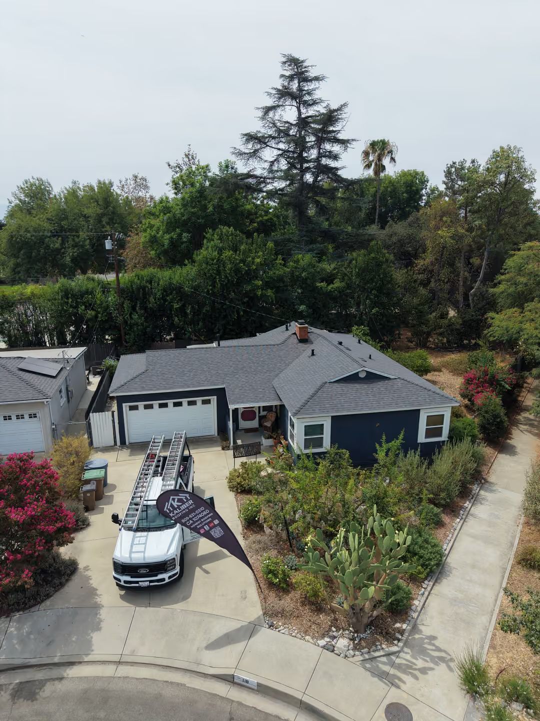 Suburban house with driveway, parked car, and landscaped front yard viewed from above