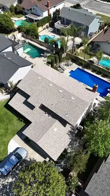 Aerial view of a residential neighborhood with houses, swimming pools, and parked cars
