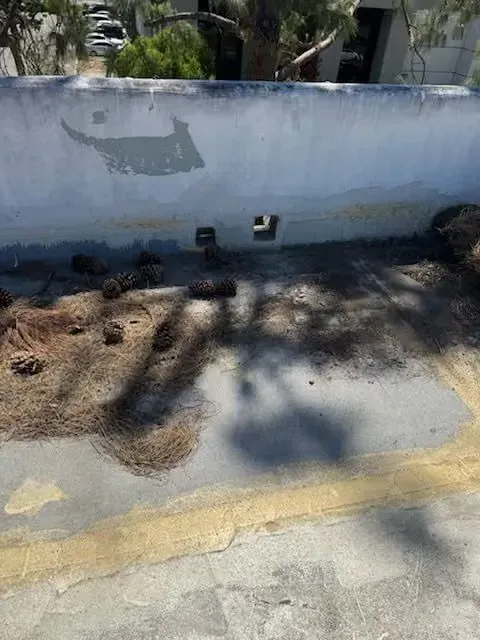 Outdoor wall with several small pipe openings and a shadowed concrete sidewalk in front