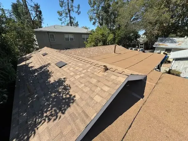 Roof with a large missing section and exposed underlayment on a residential house.
