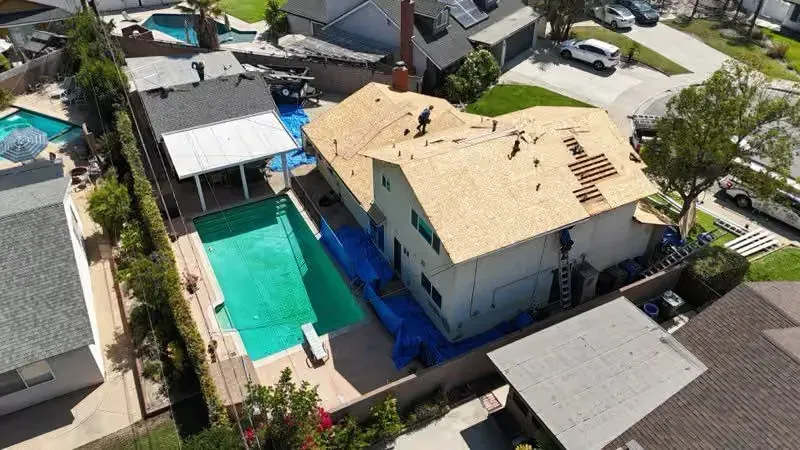 Aerial view of a house with a turquoise swimming pool and neighboring homes in a residential area