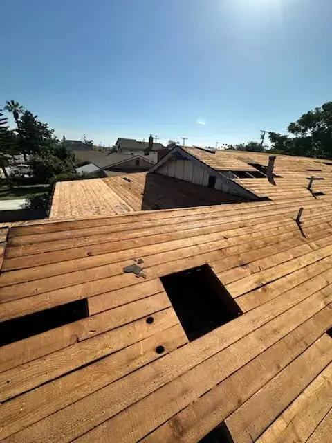 Sunlit wooden rooftop with skylights and a small central structure under a clear blue sky