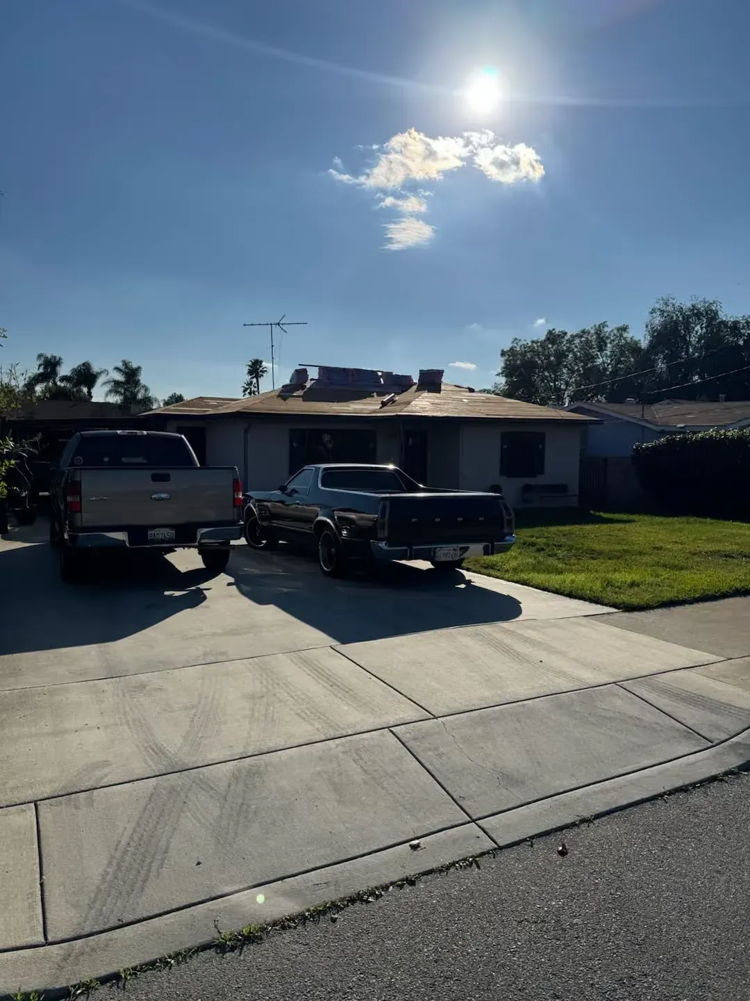 Suburban house with two parked trucks in a driveway under a bright sunny sky