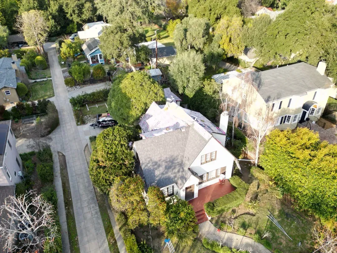 Aerial view of a suburban neighborhood with tree-lined streets and several houses with yards.
