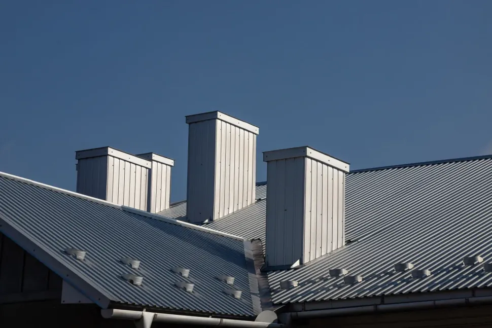 Rooftop under repair with exposed plywood, gray underlayment, and scattered roofing materials.