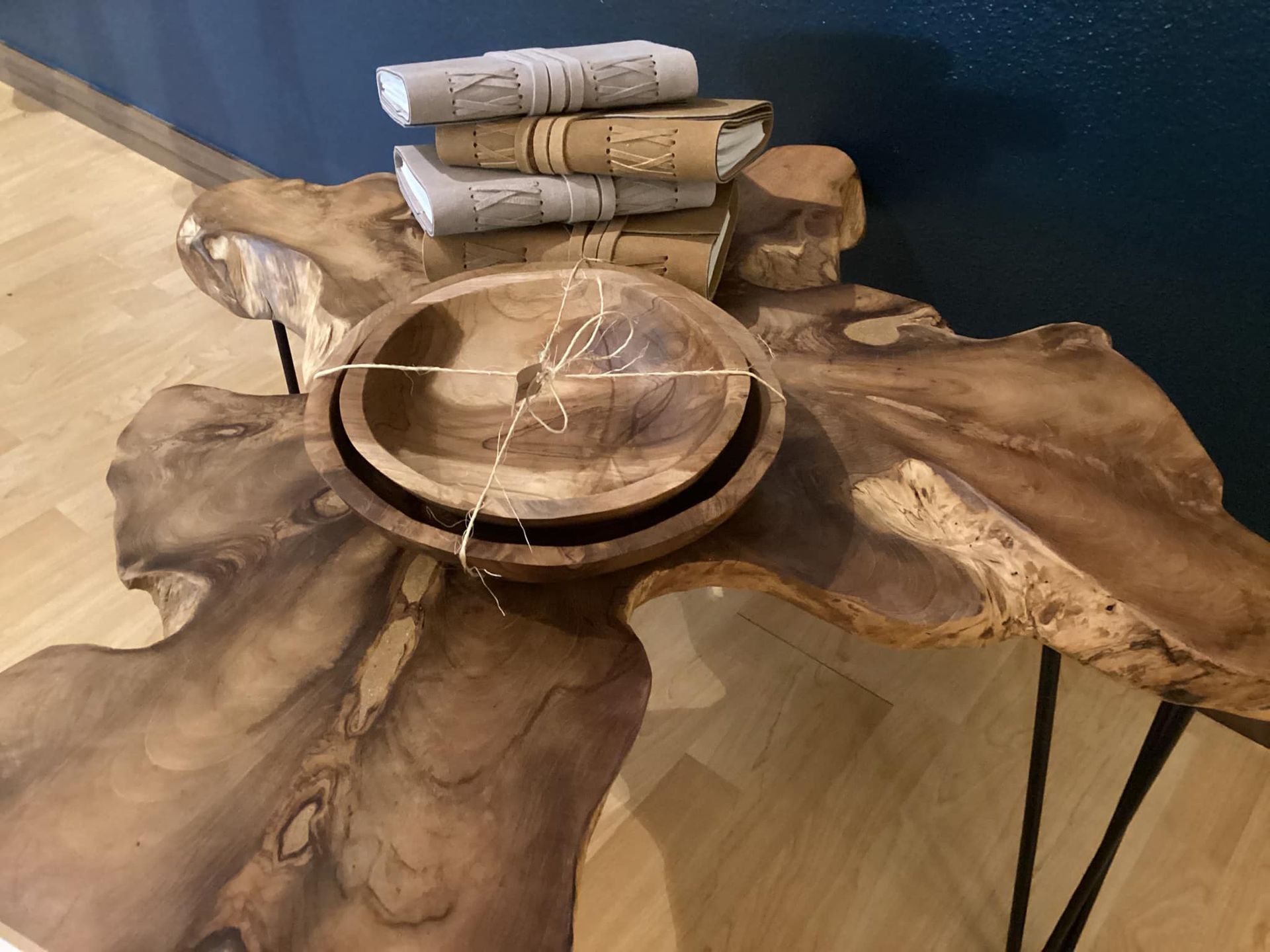 Rustic wooden coffee table with a round wooden bowl centerpiece and rolled gray napkins on top