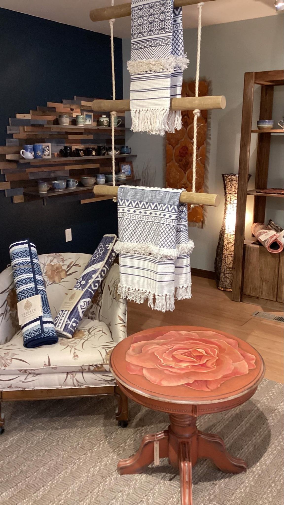 Cozy room with hanging textile art, a striped chair, and a round wooden table