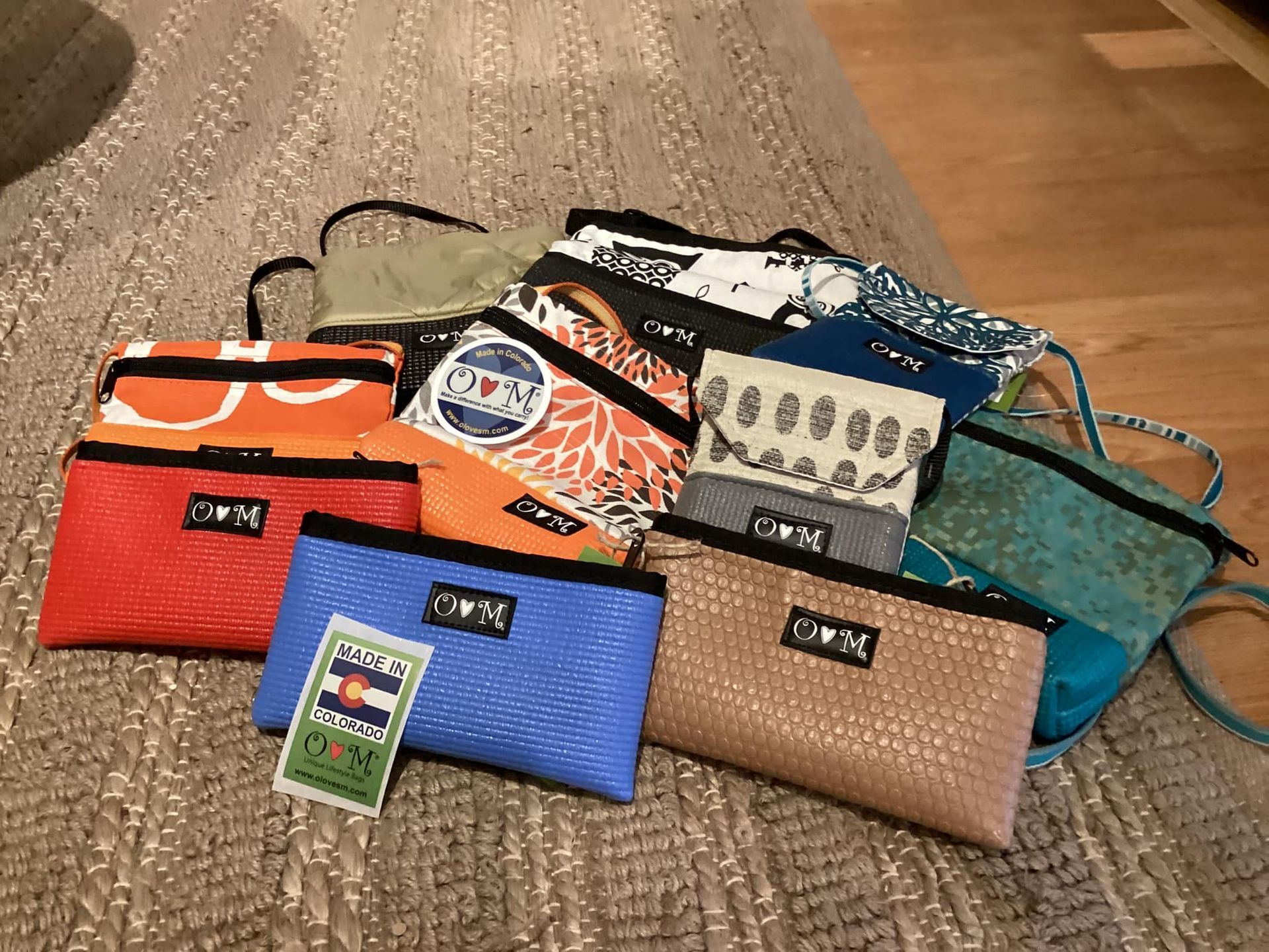 Assorted colorful zippered pouches and wallets arranged on a wooden floor