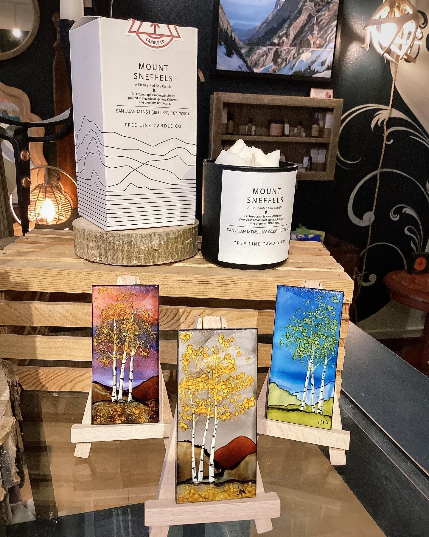 Three small stained-glass tree panels on easels at a craft display.