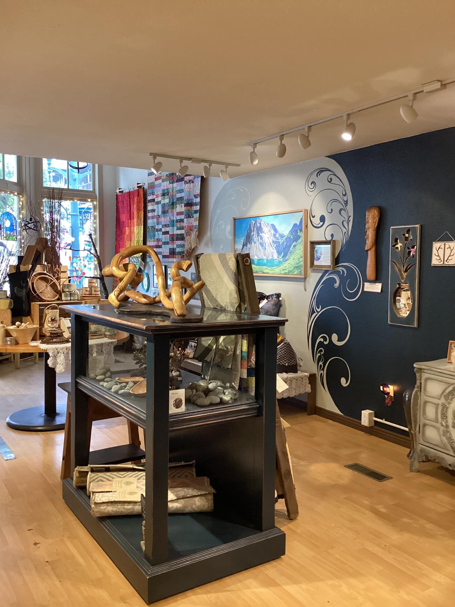 Art gallery interior with sculpture display cases, paintings, and a blue patterned wall