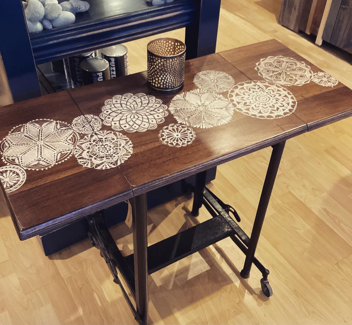 Wooden side table with white lace doilies and a candle centerpiece on a hardwood floor