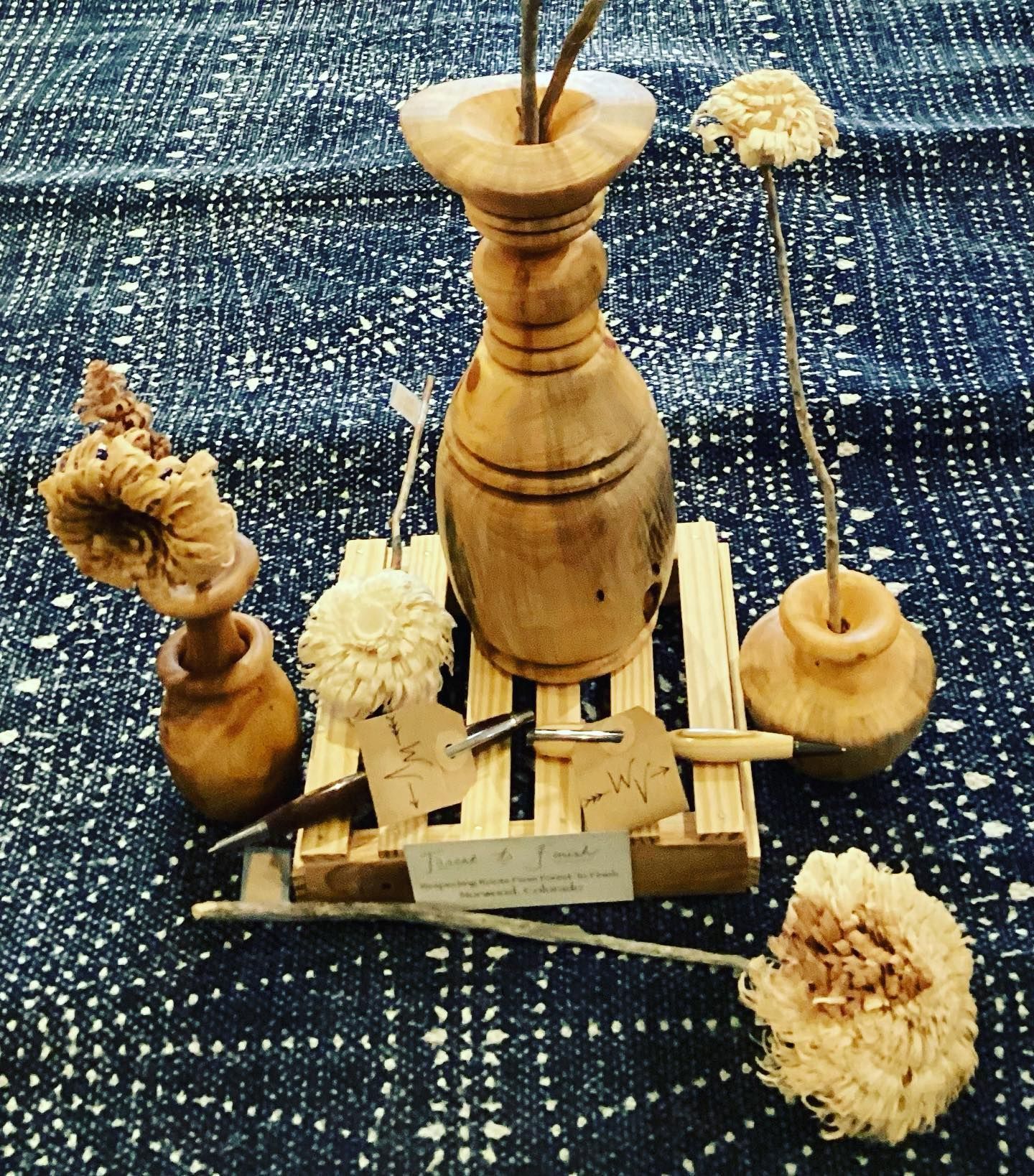Wooden spinning tops and carved pieces on a blue woven cloth backdrop