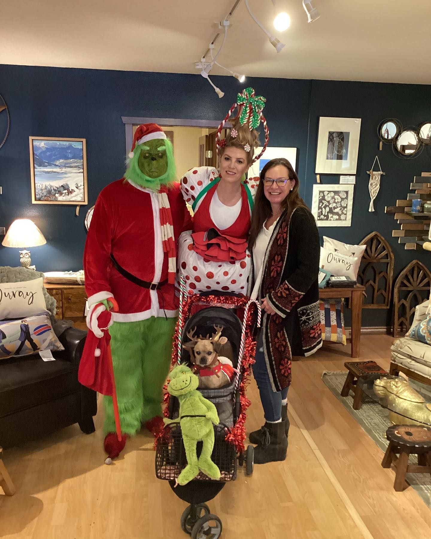 Three people and two dogs in festive holiday costumes posing in a cozy living room