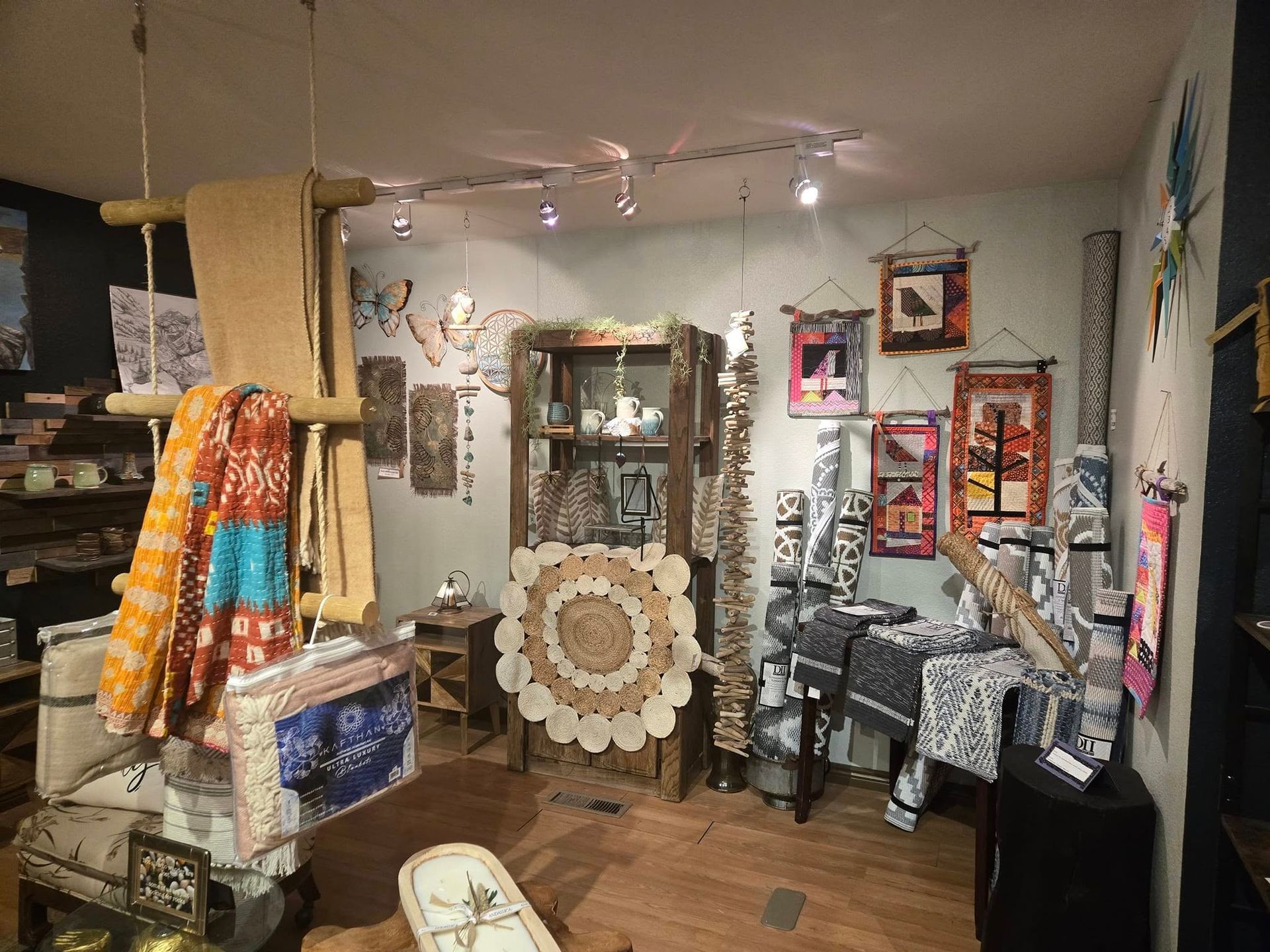 Small craft shop interior with shelves, hanging textiles, and framed artwork on display