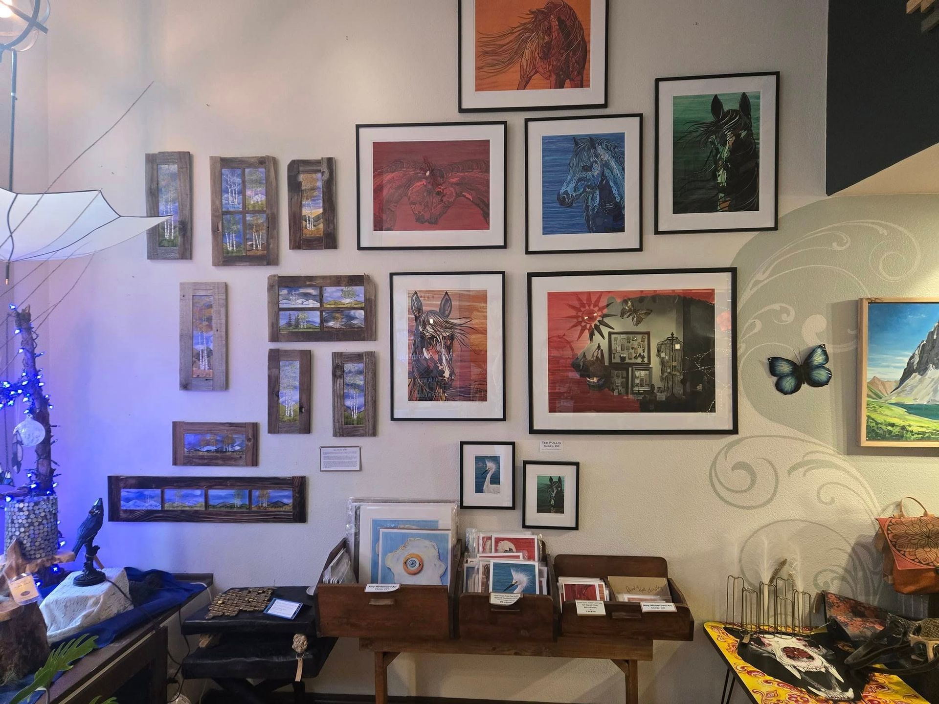 Living room wall covered with framed art, photos, and butterfly decor above a wooden console table.