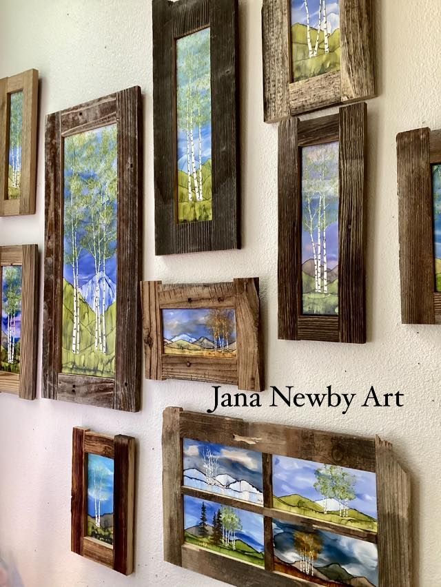 Collection of framed landscape art prints on a white wall, with “Jana Newby Art” text.