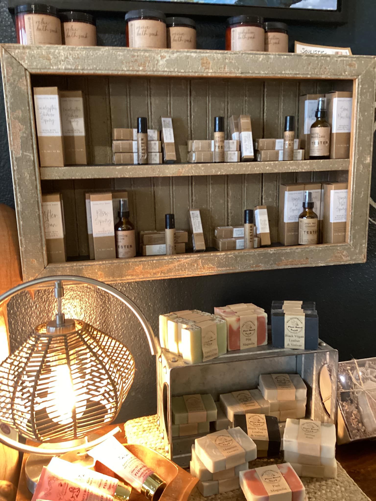 Shelf of skincare products in a rustic display, lit by a warm lamp in a cozy shop.