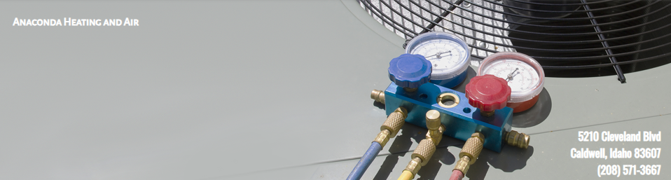 An HVAC gauge manifold set with red and blue knobs resting on a flat, gray industrial air conditioning unit.