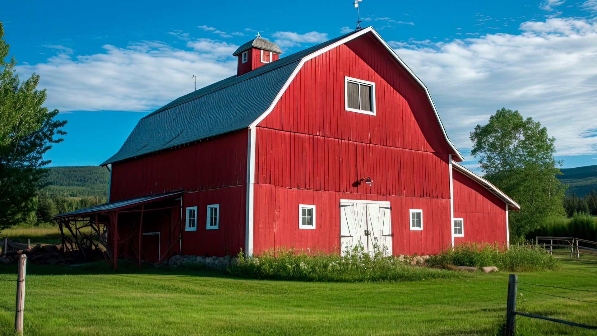 A large red barn is sitting in the middle of a grassy field.