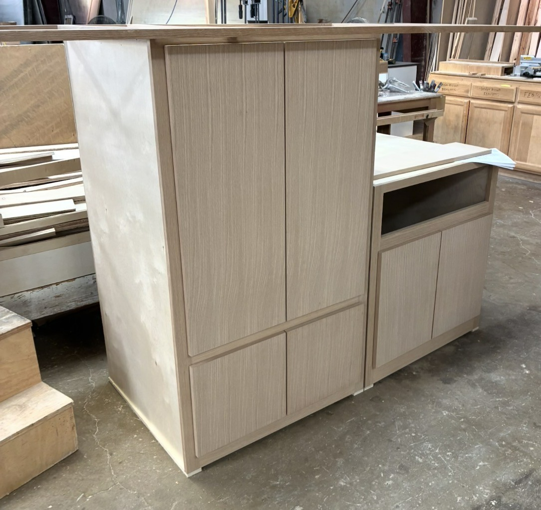 Wooden kitchen cabinets with silver handles beneath a countertop and light fixture above