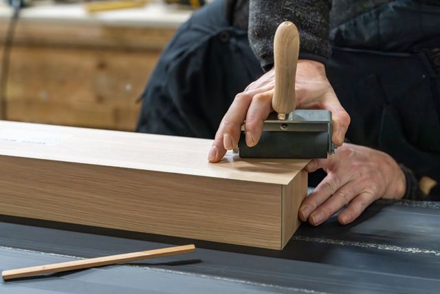 Hand planing a wooden board on a workbench with a bench plane