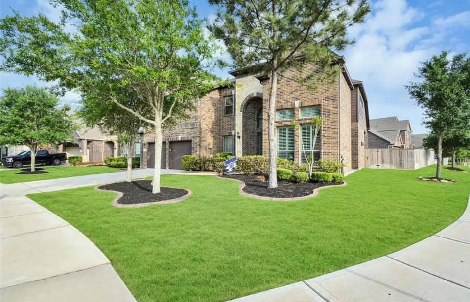Sprinkler spraying water onto green grass, in front of a building with windows.