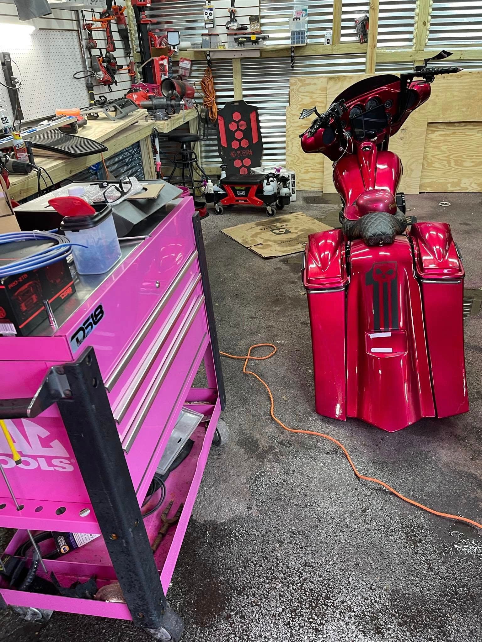 Pink custom motorcycle in a workshop with a pink tool chest.
