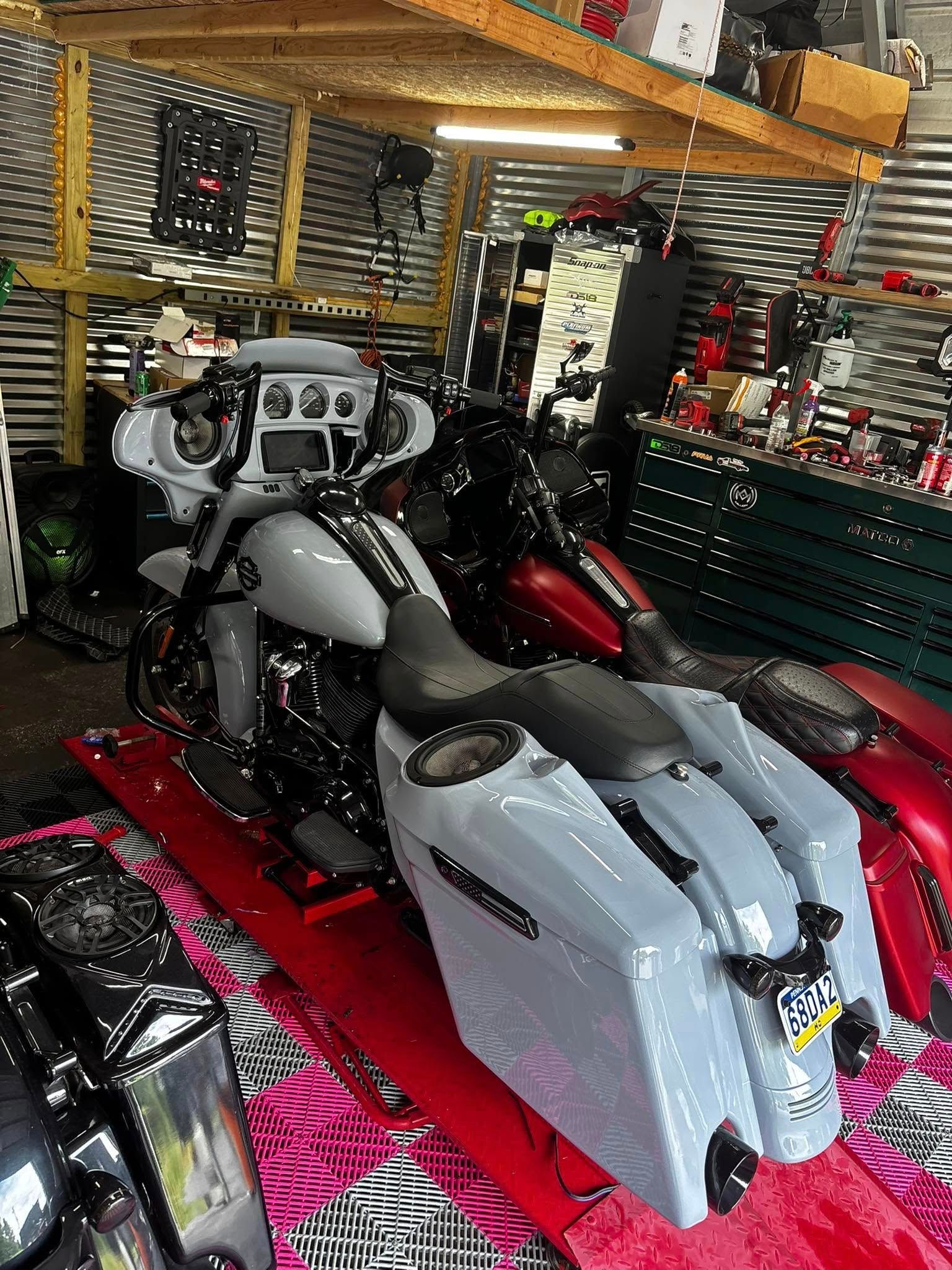 Gray and black motorcycle inside a cluttered garage, red mat underneath.