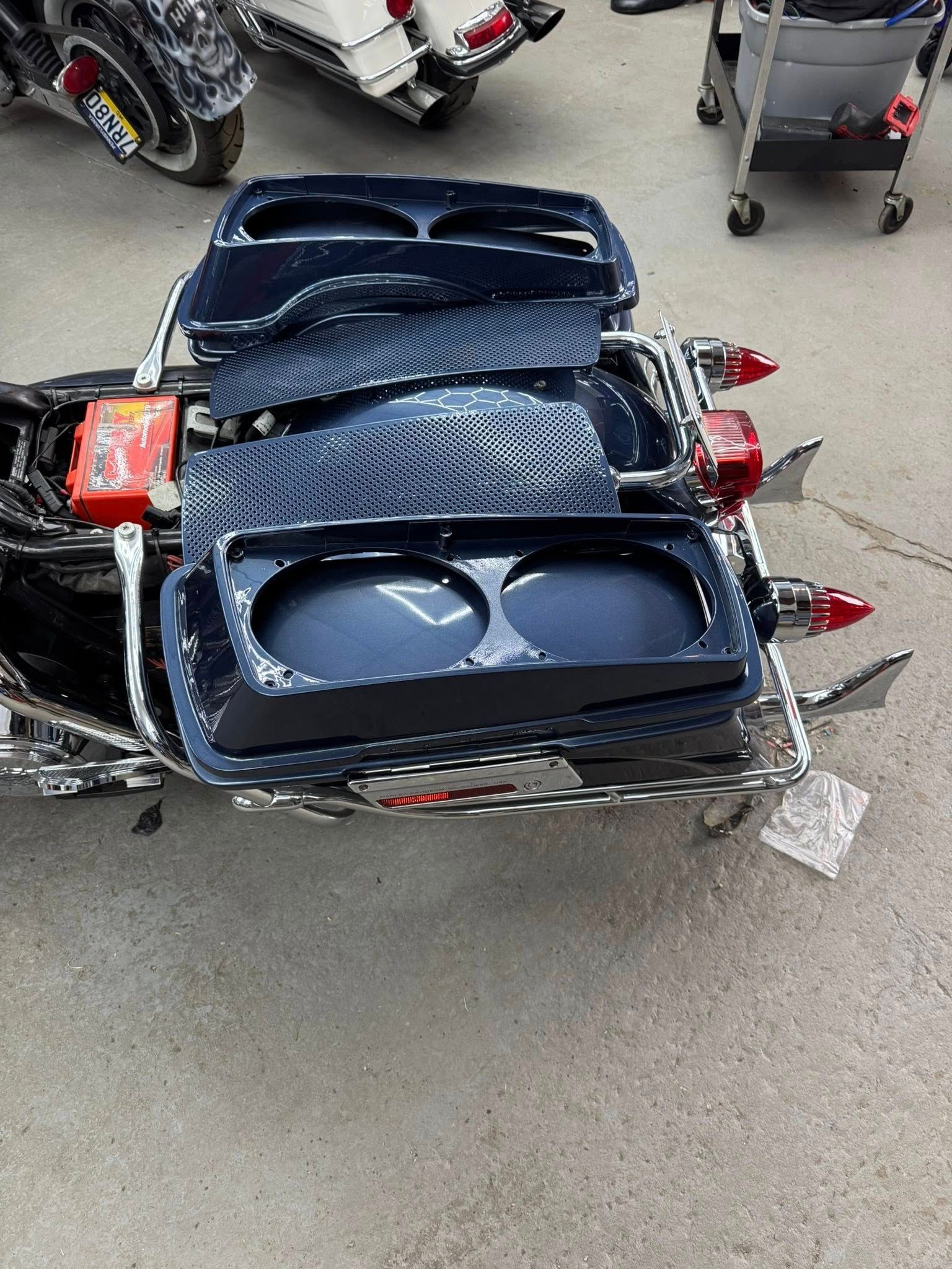 Motorcycle with black saddlebag boxes and chrome detailing, likely undergoing maintenance.
