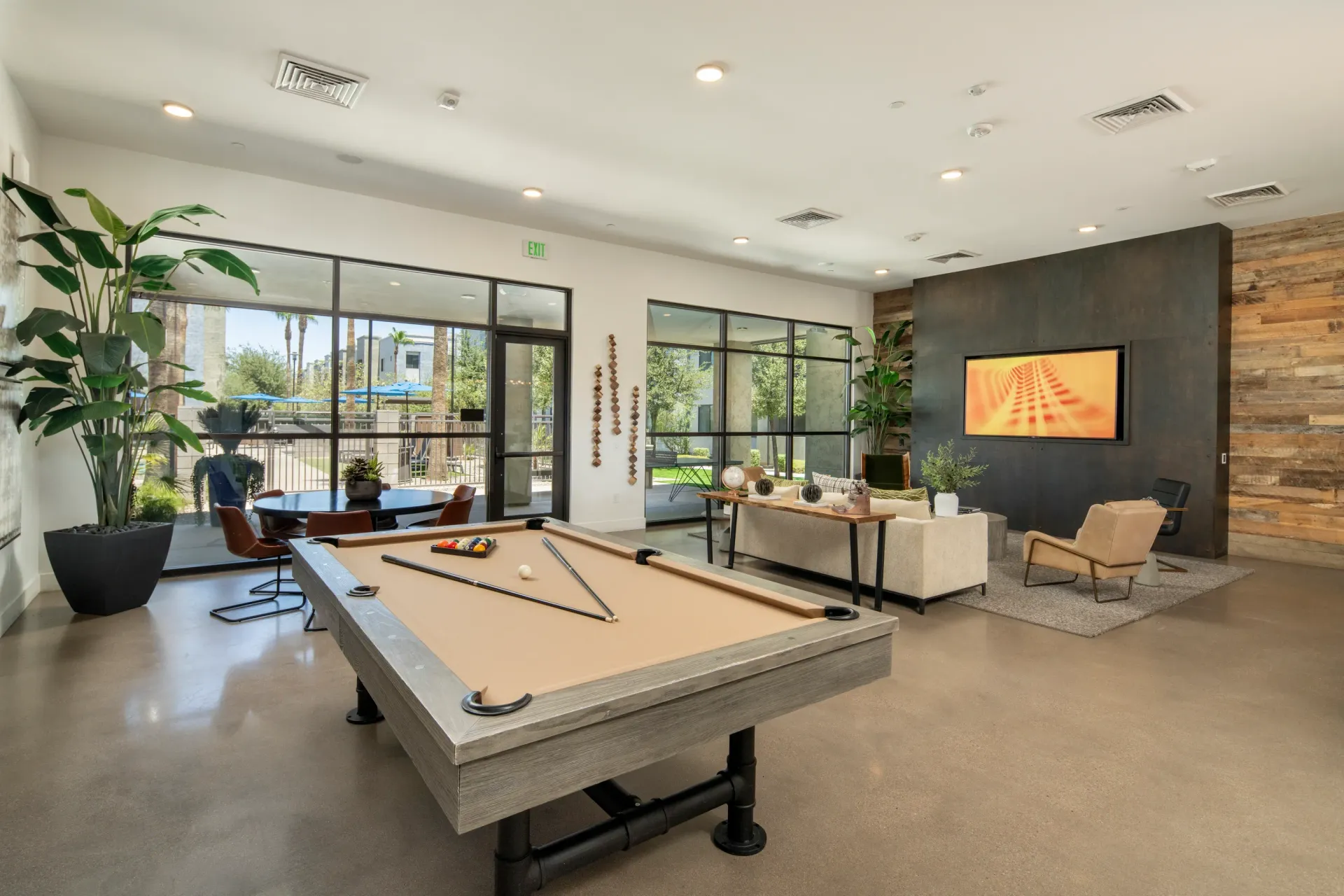 Billiard table and lounge area with TV in multifamily property's common space at Parc South Mountain in Phoenix, AZ.
