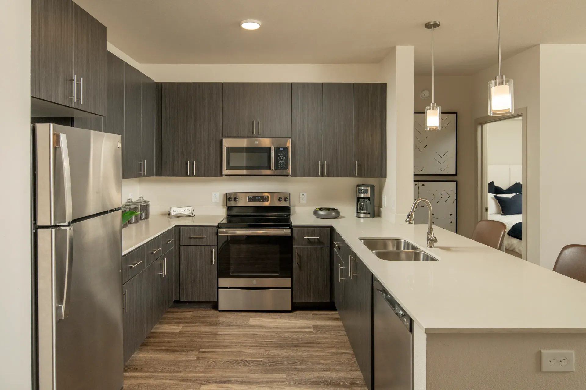 Modern U-shaped kitchen with stainless steel appliances and dark wood cabinets at Parc South Mountain in Phoenix, AZ.