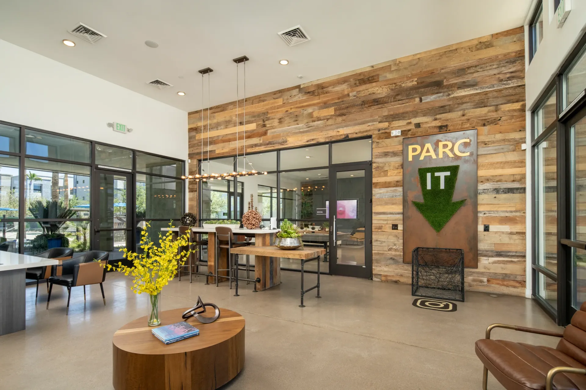Modern lounge area with seating, a communal table, and a feature wall with a