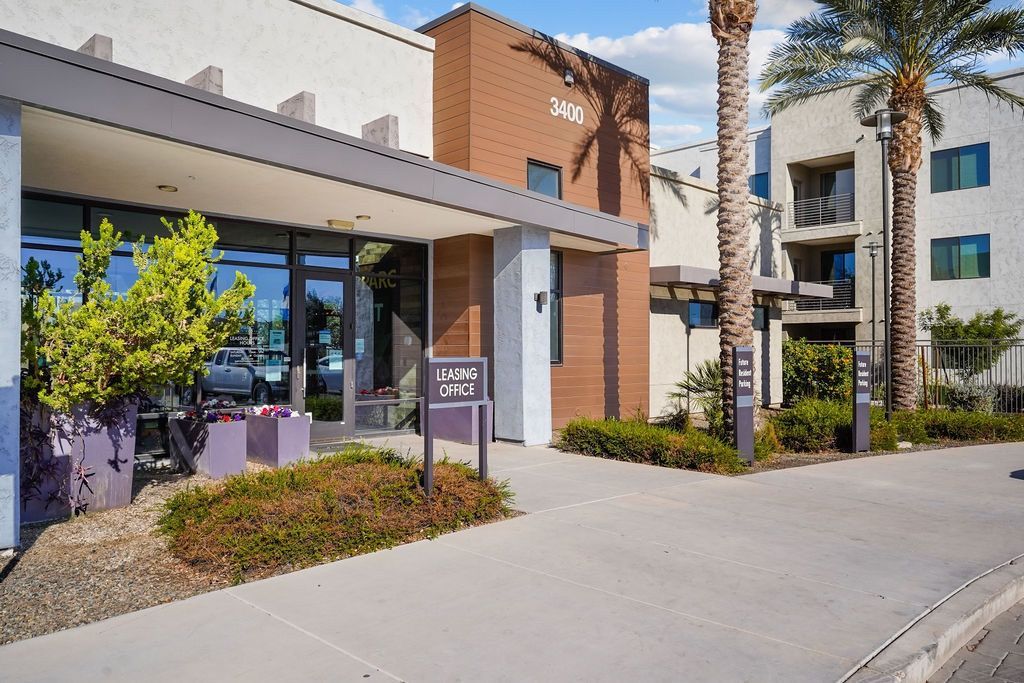 Exterior view of a modern apartment complex with leasing office entrance and signage at Parc South Mountain in Phoenix, AZ.