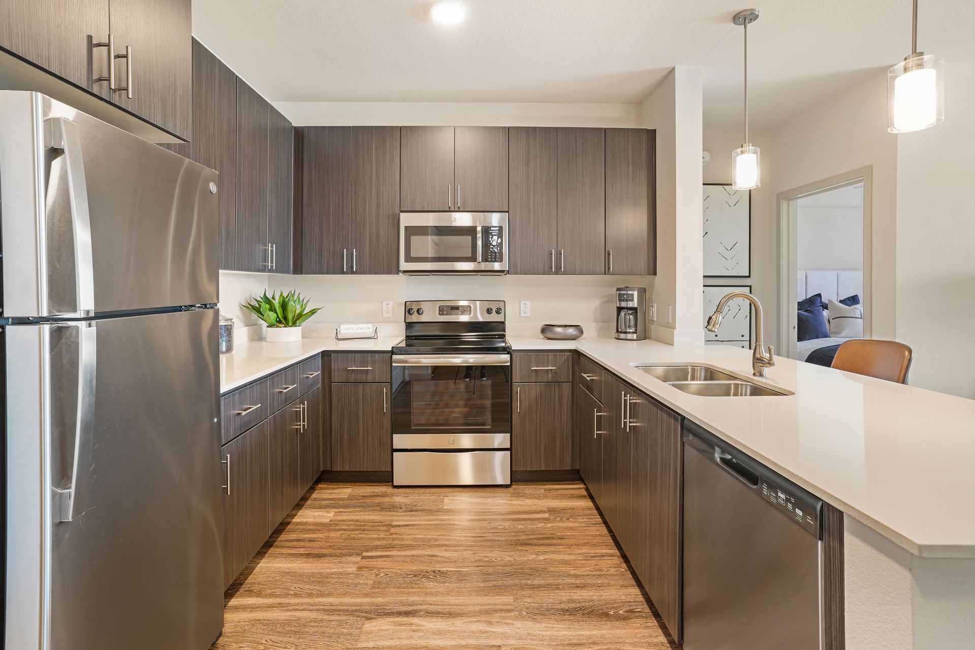 Modern kitchen with stainless steel appliances, dark wood cabinets, and white countertops at Parc South Mountain in Phoenix, AZ..