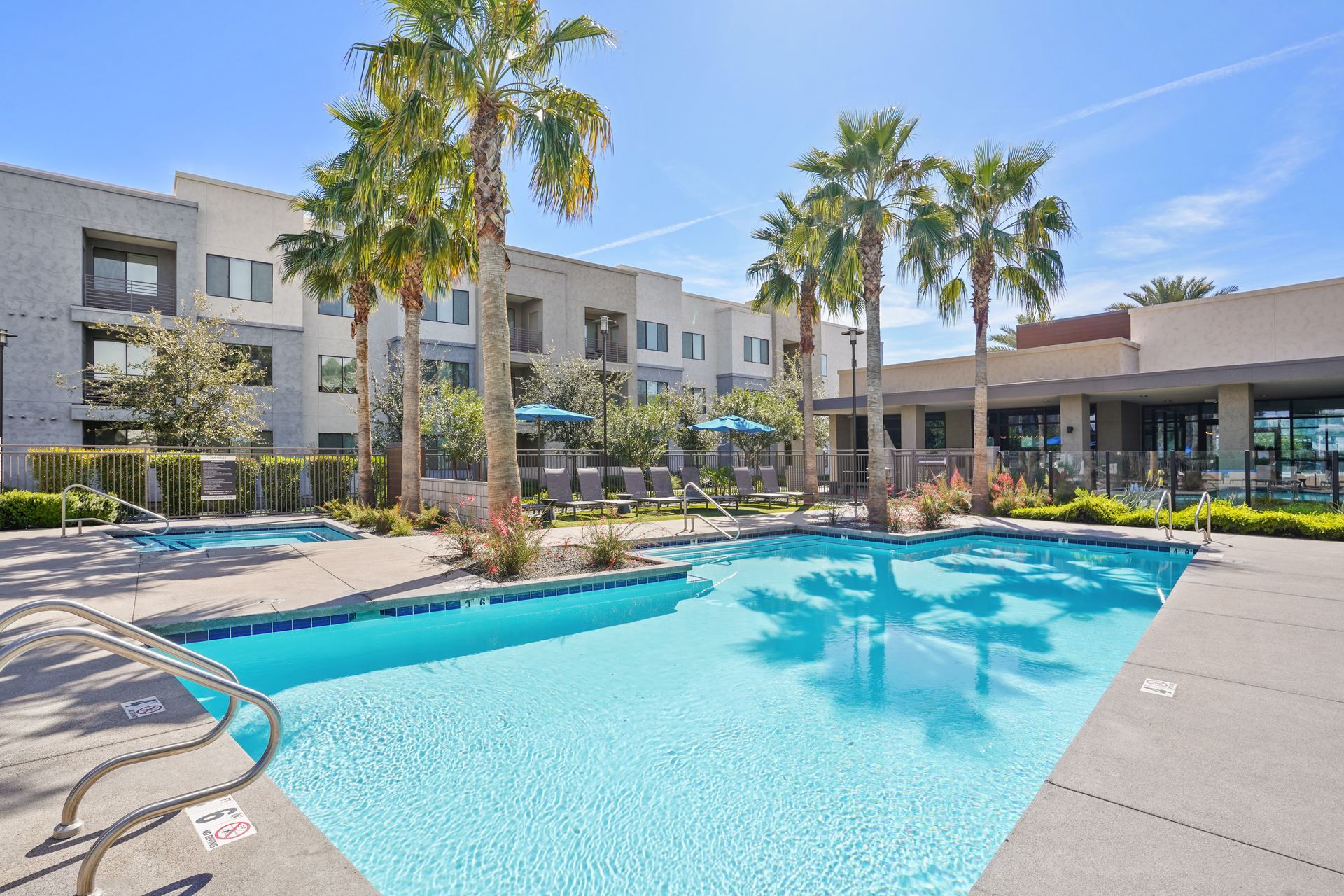 Swimming pool and spa surrounded by palm trees and apartment buildings at Parc South Mountain in Phoenix, AZ..