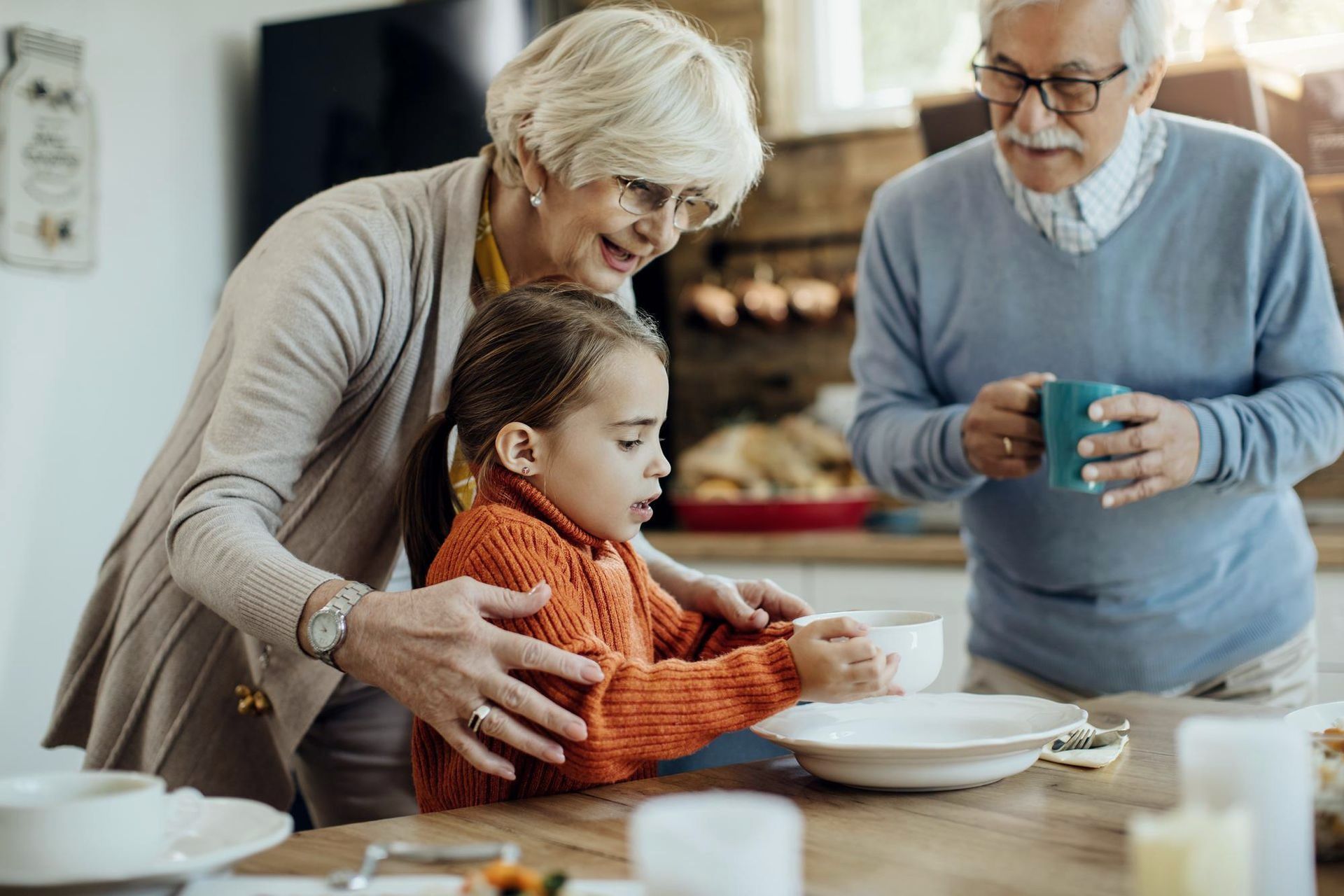 Grandparents helping a young girl at a table.