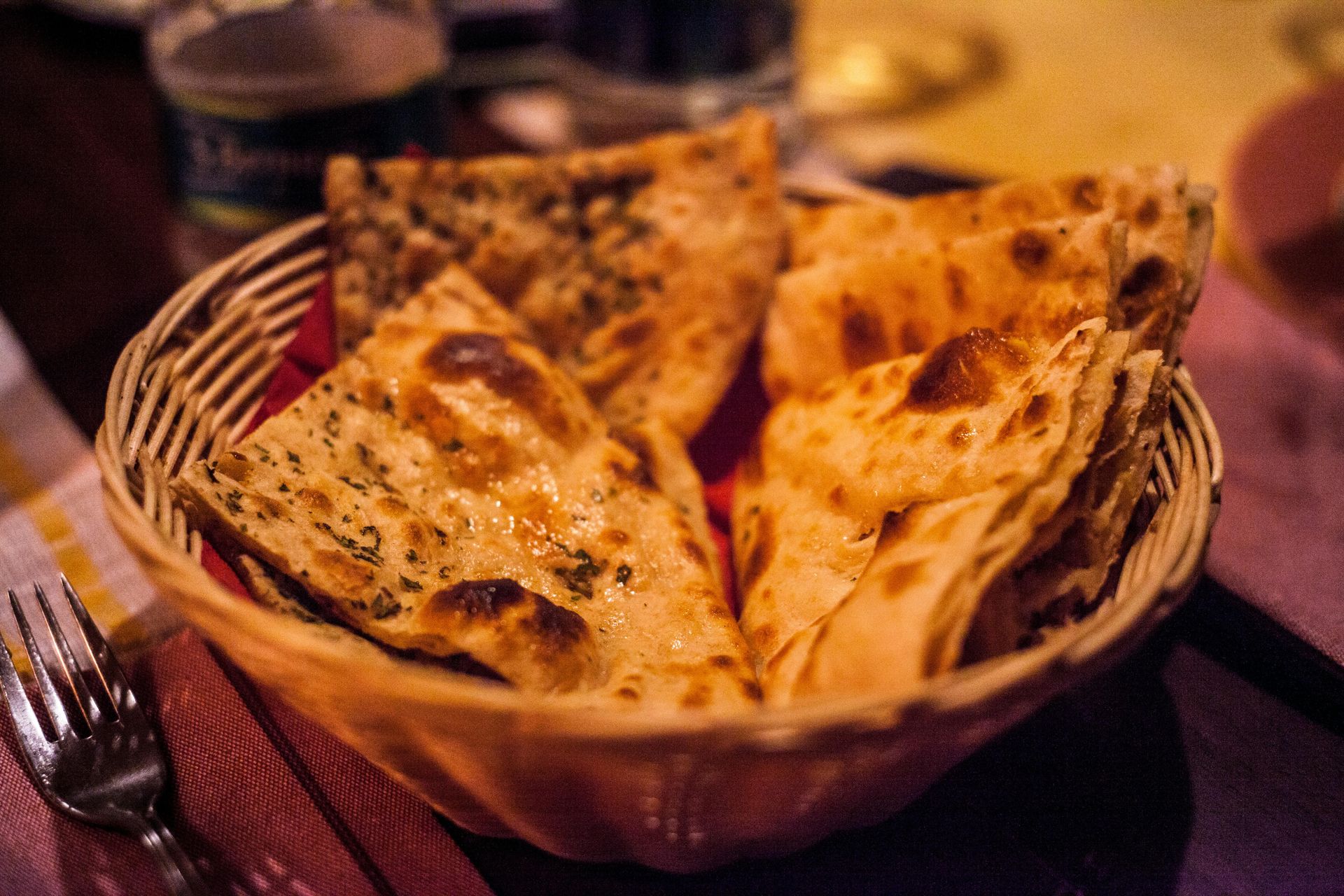 Basket of toasted flatbread wedges on a table with a fork nearby