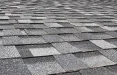 Worker removing damaged shingles from a roof during repairs