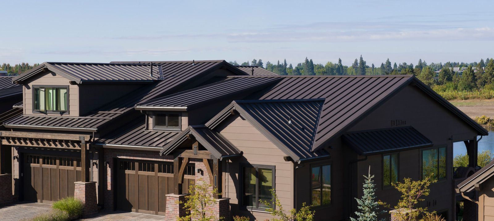 Modern dark-gray suburban house with a tiled roof and garage under a clear sky