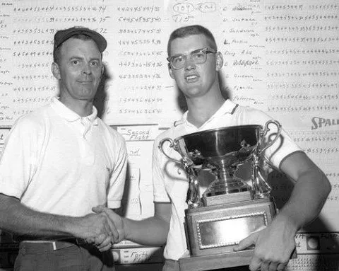 Two men are shaking hands while holding a trophy.
