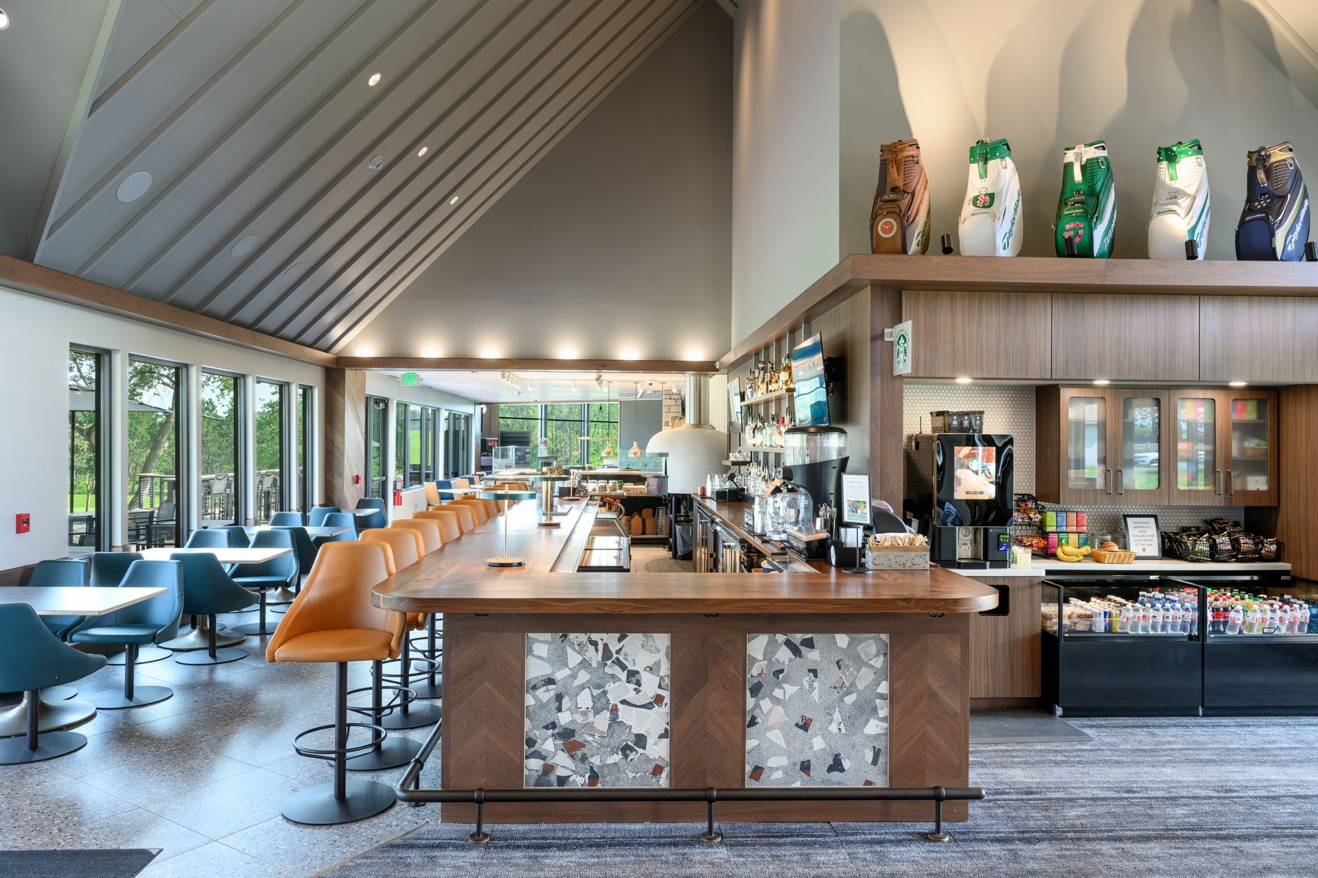 A restaurant with a long bar and tables and chairs.