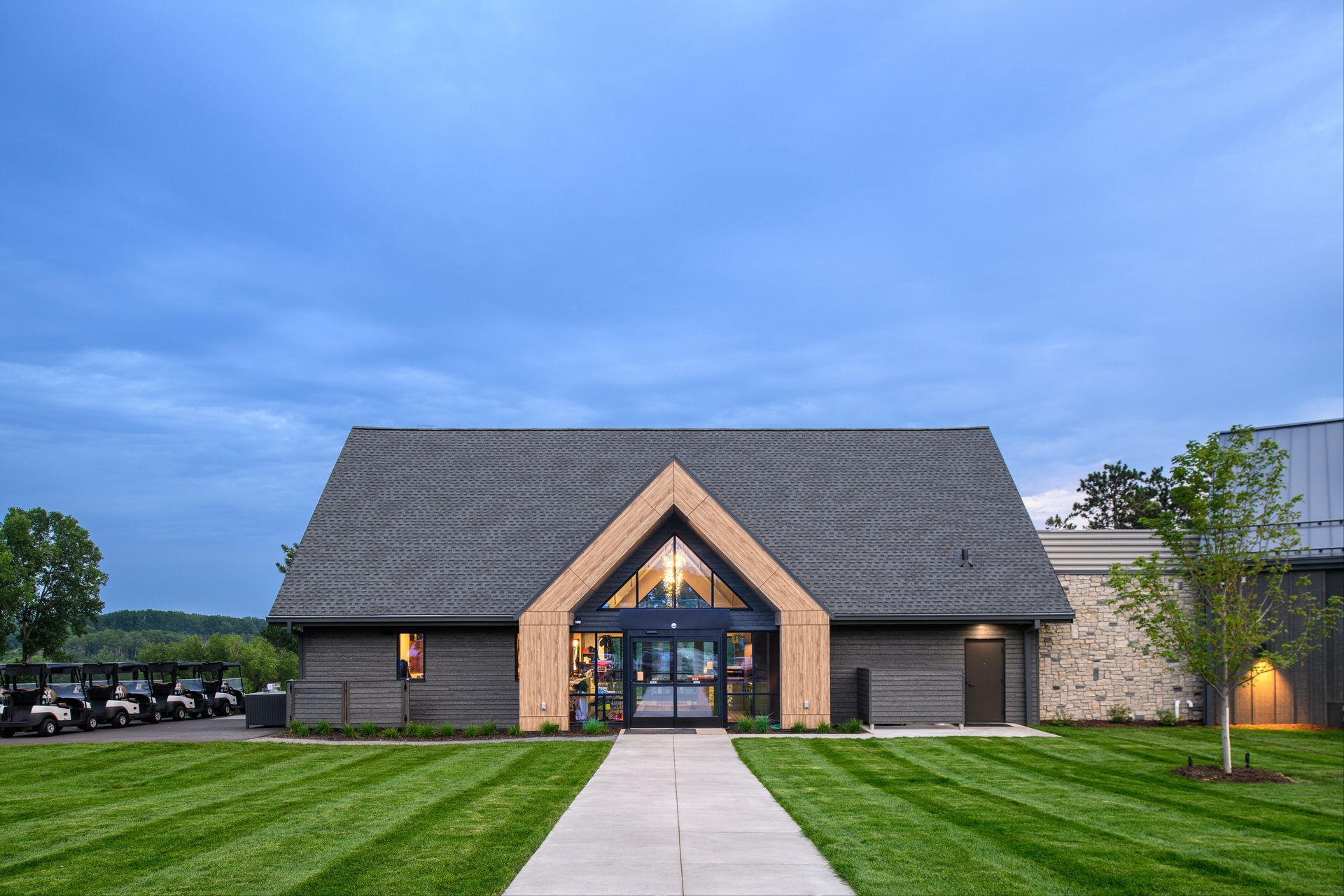 A large building with a gray roof and a walkway leading to it.